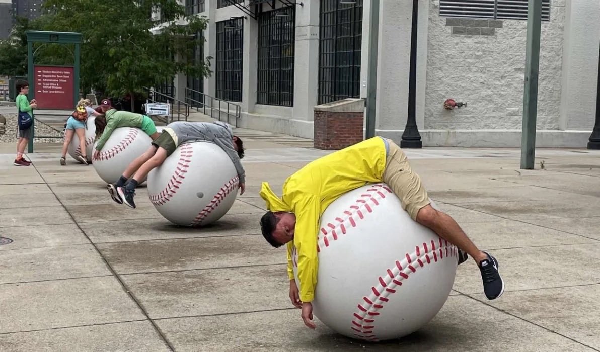 A player hugs a giant baseball sculpture in Downtown Dayton